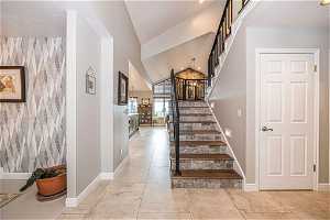 Stairs featuring vaulted ceiling and light tile floors