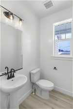 Half Bathroom featuring hardwood / wood-style floors and toilet