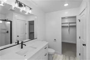Primary bathroom featuring Dual Sink vanity with extensive cabinet space, hardwood / wood-style floors, a shower with shower door, and toilet