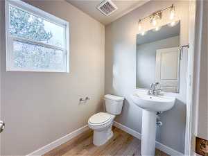 Bathroom with plenty of natural light, a textured ceiling, toilet, and hardwood / wood-style flooring