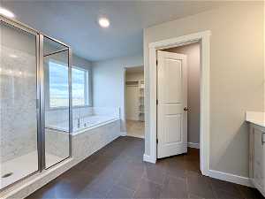 Bathroom featuring a textured ceiling, tile flooring, vanity, and independent shower and bath