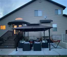 Twilight Back of property with a gazebo, an outdoor hangout area, and a patio