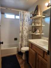 Full guest bathroom with toilet, tile floors, shower / tub combo with curtain, and vanity with extensive cabinet space