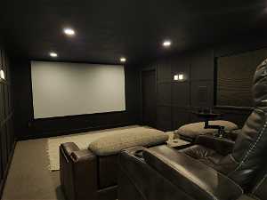 View of carpeted cinema with large viewing screen and basement walkout