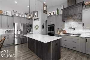 Kitchen with decorative light fixtures, a center island, dark wood-type flooring, appliances with stainless steel finishes, and backsplash