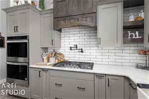 Kitchen featuring backsplash, stainless steel appliances, and gray cabinets