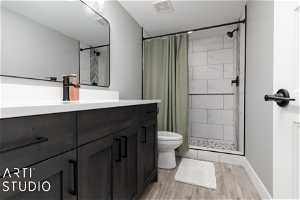 Bathroom with wood-type flooring, toilet, a shower with shower curtain, and vanity