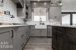 Kitchen featuring dark hardwood / wood-style flooring, tasteful backsplash, gray cabinets, dishwasher, and sink