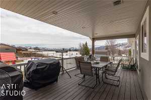 Snow covered deck featuring a mountain view and grilling area