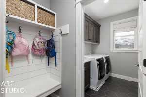 Interior space featuring dark tile flooring, washer and clothes dryer, and cabinets