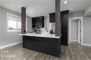 Kitchen featuring light wood-type flooring, a center island, appliances with stainless steel finishes, and sink