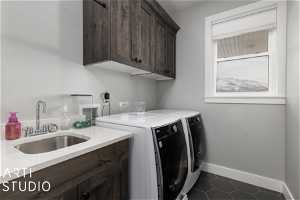 Clothes washing area featuring washer and clothes dryer, dark tile floors, sink, and cabinets