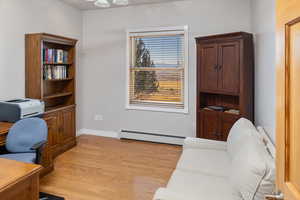 Home office with a baseboard heating unit and light wood-type flooring