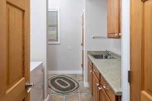 Washroom with cabinets, light tile flooring, sink, and washer / dryer