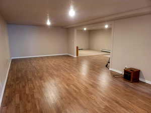 Basement with light wood-type flooring and a baseboard heating unit