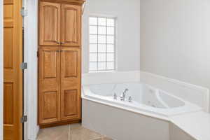 Bathroom featuring tile flooring, plenty of natural light, and a bath