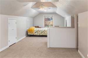 Bedroom with lofted ceiling, ceiling fan, and light carpet