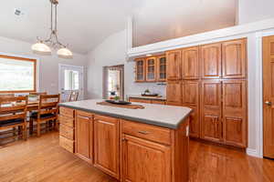 Kitchen with hanging light fixtures, light hardwood / wood-style flooring, a chandelier, and a center island