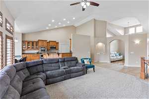 Family room featuring ceiling fan, light carpet, and high vaulted ceiling