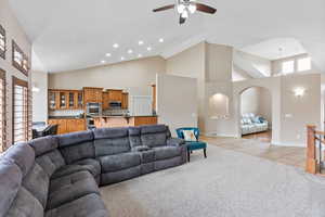 Family room featuring ceiling fan, light carpet, and high vaulted ceiling