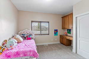 View of carpeted bedroom with built-in desk/cabinets with en suite bathroom