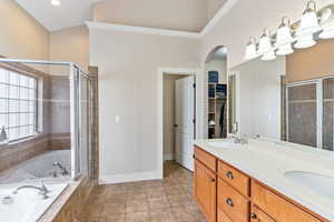 Bathroom featuring crown molding, shower with separate bathtub, dual bowl vanity, and tile flooring