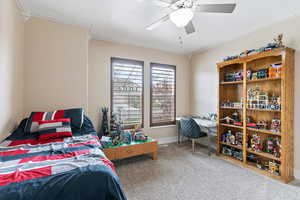 Carpeted bedroom featuring ceiling fan and ornamental molding