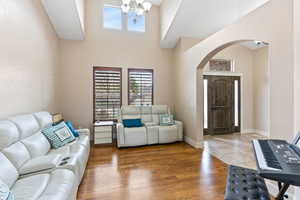 Living room with dark hardwood / wood-style flooring, a notable chandelier, and a high ceiling