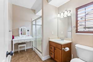 En suite bathroom featuring tile flooring, a shower with shower door, vanity and extensive cabinet space and toilet