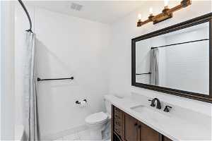 Full bathroom featuring toilet, shower / tub combo with curtain, tile flooring, and vanity with extensive cabinet space