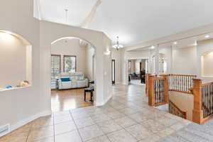 Tiled entryway with a notable chandelier and high vaulted ceiling