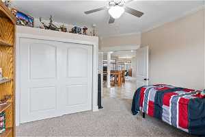 Bedroom with ceiling fan, crown molding, a closet, and light carpet
