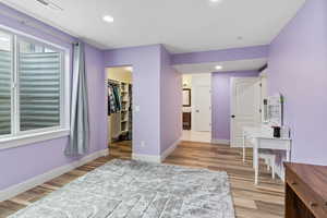 Bedroom featuring a spacious walk-in closet, light wood-type flooring, linen closet and en suite bathroom