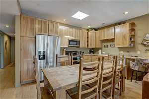 Kitchen featuring light brown cabinets, stainless steel appliances, sink, and light hardwood / wood-style flooring
