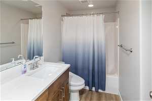 Full bathroom featuring shower / tub combo, hardwood / wood-style floors, toilet, and oversized vanity