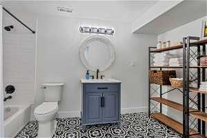 Full bathroom with tile floors, toilet, vanity, and tiled shower / bath