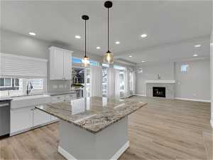 Kitchen featuring pendant lighting, a kitchen island, light hardwood / wood-style floors, and white cabinets