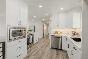 Kitchen with appliances with stainless steel finishes, light wood-type flooring, and white cabinetry
