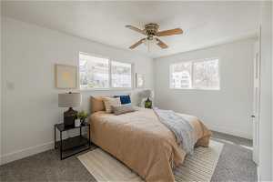 Carpeted bedroom featuring ceiling fan and multiple windows