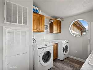 Laundry area featuring dark wood-type flooring, washing machine and clothes dryer, washer hookup, a textured ceiling, and cabinets