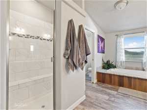 Bathroom featuring a textured ceiling, toilet, separate shower and tub, and wood-type flooring
