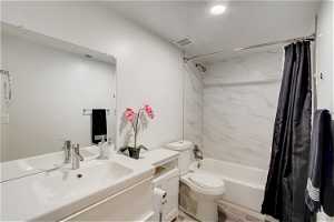 Full bathroom with shower / tub combo with curtain, hardwood / wood-style flooring, toilet, and vanity