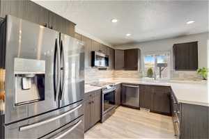 Kitchen featuring appliances with stainless steel finishes, tasteful backsplash, light hardwood / wood-style floors, and sink