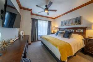 Bedroom with ceiling fan, dark colored carpet, a textured ceiling, and crown molding
