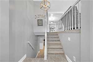 Stairway with an inviting chandelier and light tile floors