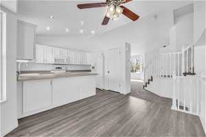 Kitchen with hardwood / wood-style floors, ceiling fan, white appliances, sink, and white cabinets