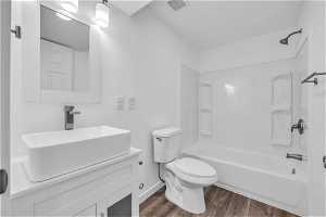 Basement full bathroom featuring vanity, toilet, hardwood / wood-style flooring, and bathtub / shower combination