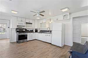 Kitchen with white cabinets, ceiling fan, white appliances, and light hardwood / wood-style flooring