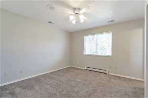 Primary bedroom with ceiling fan, a baseboard radiator, and light colored carpet