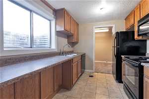 Kitchen with sink, light tile floors, black appliances, and  natural light